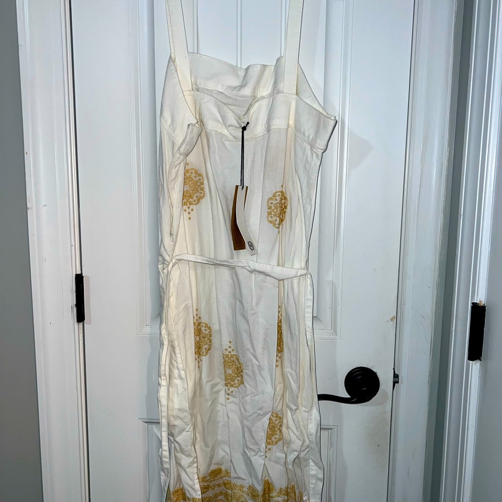 White linen dress with some gold details.